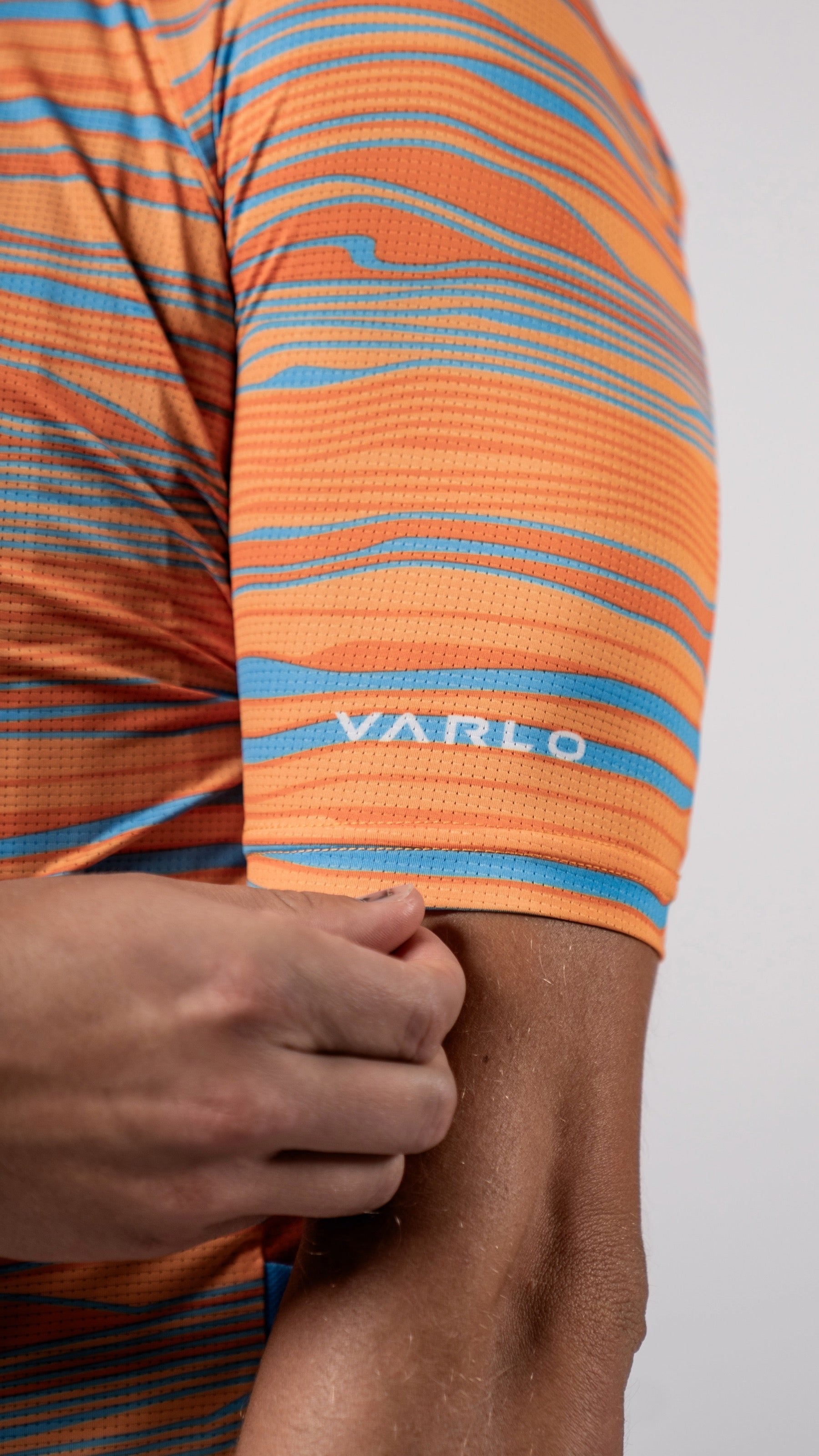 Close up of left sleeve and Varlo logo on the new 2025 gravel series pioneer cycling jersey in path orange.