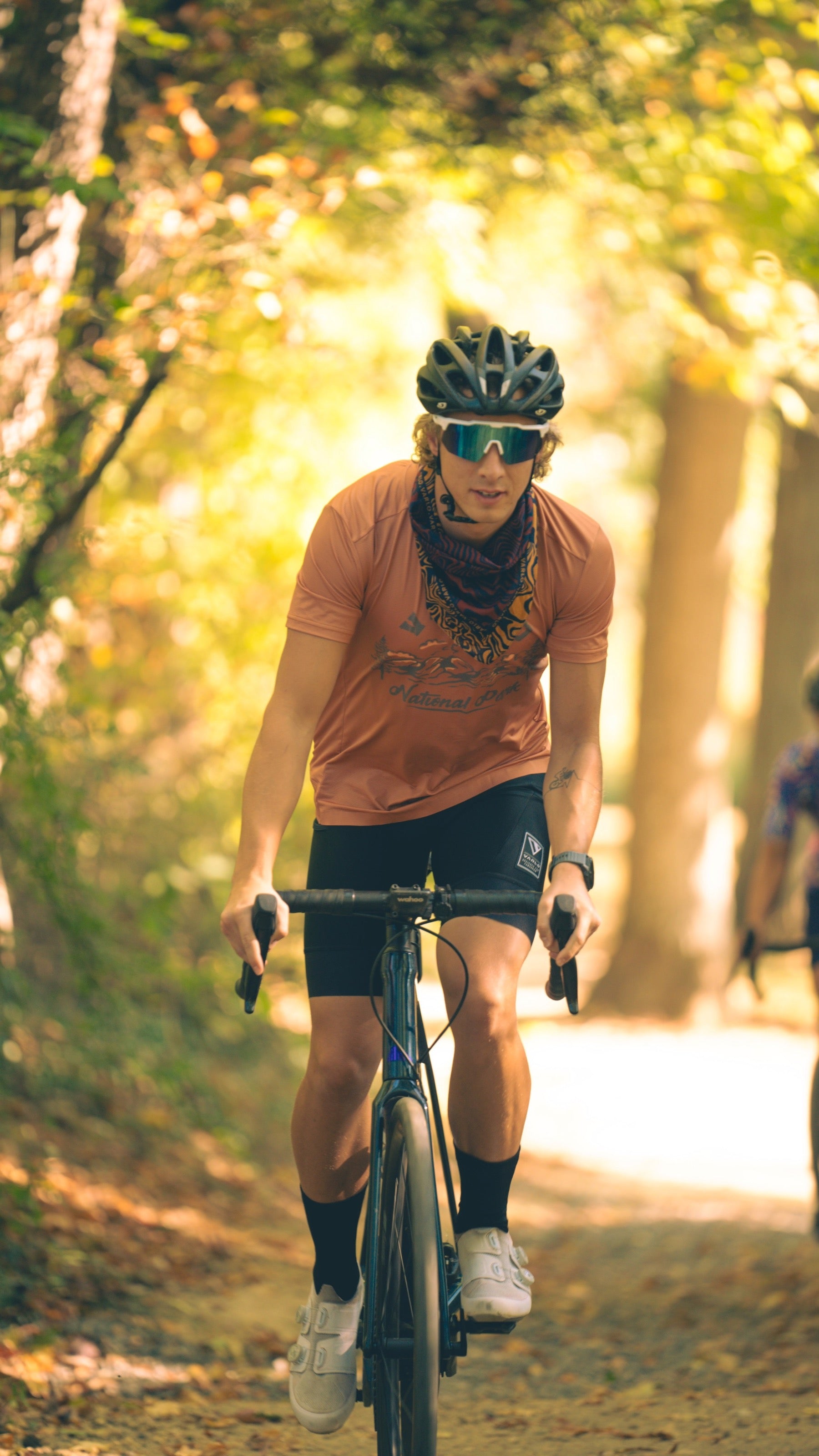 Lifestyle of the Varlo mens parkroad tan explorer cycle crew shirt on a wooded gravel trail.