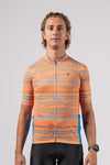 Front view in studio of male model of the pioneer gravel jersey in path orange from the Varlo 2025 gravel series.